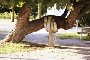 Une statue en forme de main qui soutien une grosse branche d'un chêne pour imager les stratégies mises en place par le dépendant affectif pour rester debout émotionnellement